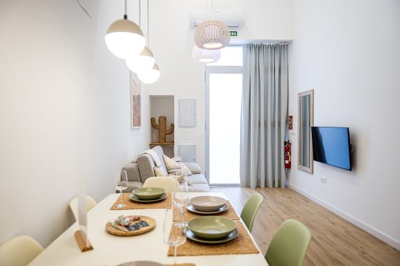 Comedor moderno con mesa dispuesta y ventanales iluminados. امکانات adicionales en la pared.